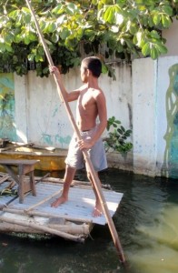 A boy rows a skiff down a flooded street in Rizal Province, Philippines